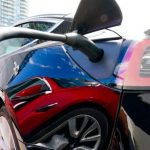 EV rebates charging costs - Electric vehicle plugged into charging station with power cable connected