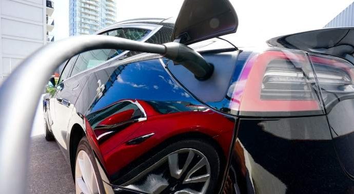 EV rebates charging costs - Electric vehicle plugged into charging station with power cable connected