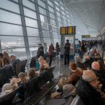 flight delays Canada - Snow-covered aircraft and airport runway during winter storm causing flight delays