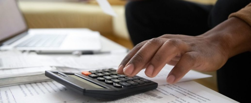 hidden home buying costs - Calculator and house keys on financial documents showing home buying costs