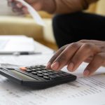 hidden home buying costs - Calculator and house keys on financial documents showing home buying costs
