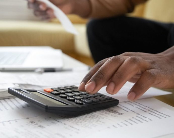 hidden home buying costs - Calculator and house keys on financial documents showing home buying costs