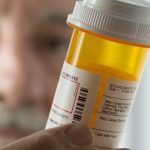 national pharmacare program - Pharmacist dispensing prescription medications at pharmacy counter
