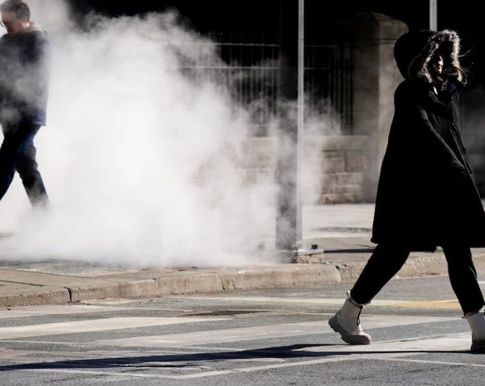 GTHA wind chill warning - Person bundled up walking in extreme cold weather with visible breath in winter conditions